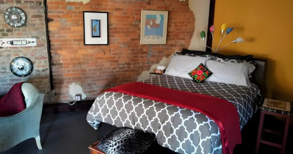 A brick-walled loft bedroom with a mustard accent wall on Historic C-Street.