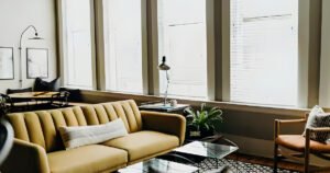 A sunlit loft living room with a yellow sofa and tall historic windows on Historic C-Street.