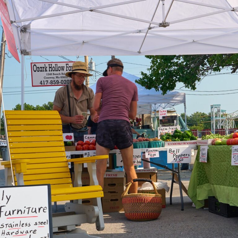 A farmer in a straw hat makes change at the Ozark Hollow Farm produce stand at the C-Street City Market.