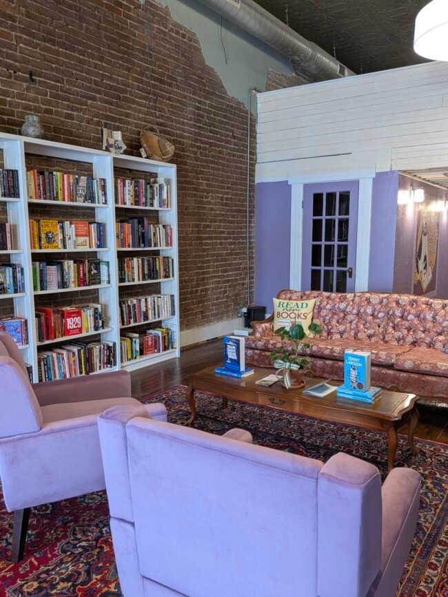 The reading lounge at One More Page bookstore on Historic C-Street, with white shelves against exposed brick.