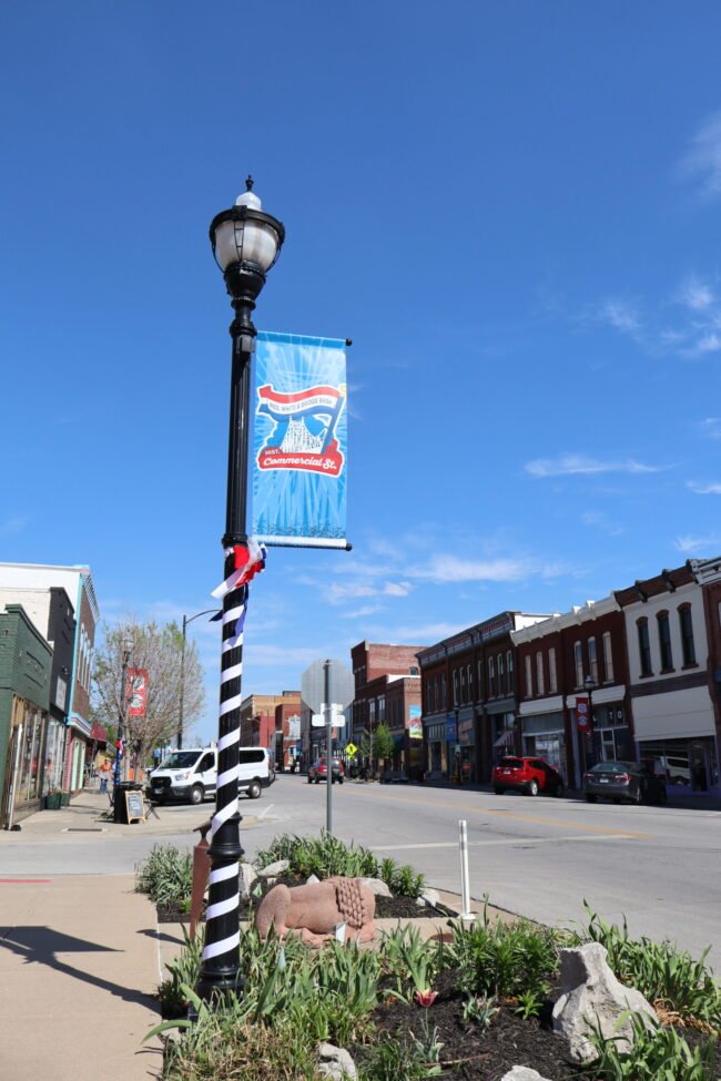 A decorated Commercial Street lamppost and banner rise over spring tulips on Historic C-Street.