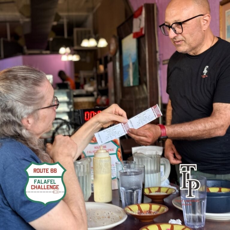 A That Lebanese Place owner hands concert tickets to a Route 66 Falafel Challenge finisher.