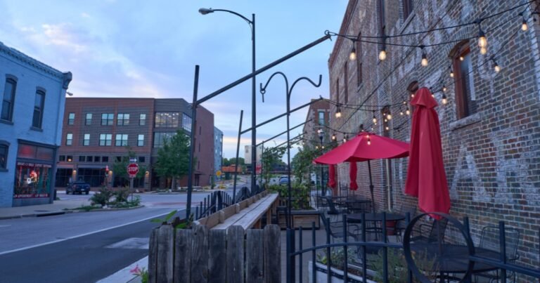 A Historic Commercial Street patio with red umbrellas and string lights at dusk, Springfield, Missouri.