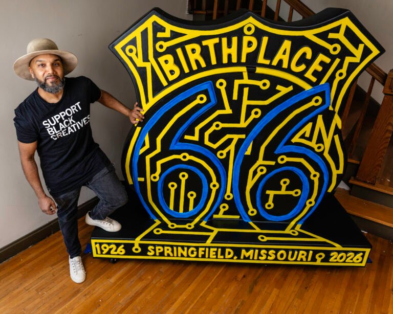 Artist Yves Hu Jerome beside the painted Birthplace 66 Route 66 sculpture on Historic C-Street, Springfield, Missouri.